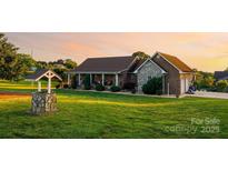 Beautiful brick home featuring a well, lush lawn, and a charming covered front porch at sunset at 2843 Startown Rd, Lincolnton, NC 28092