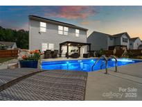 Inviting backyard oasis features a sparkling pool, lounge chairs, and pergola seating, perfect for relaxing and entertaining at 3092 Riker St, Clover, SC 29710