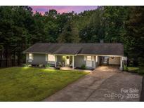 Serene evening view of a cozy single-story home with lush lawn, covered entry, and convenient carport at 312 Walton Dr, Statesville, NC 28625