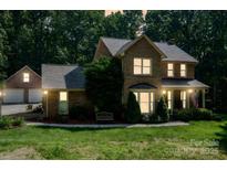 Charming brick home with mature trees, front porch, two-car garage, and well-manicured lawn at 3513 Briarcliff Acres Dr, Lincolnton, NC 28092