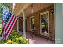Inviting front porch with American flag, brick columns, and small table at 3513 Briarcliff Acres Dr, Lincolnton, NC 28092