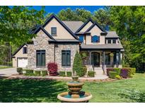 Beautiful stone and stucco home featuring a manicured lawn, lush landscaping and a charming fountain at 546 Little Cove Ln, Lake Wylie, SC 29710