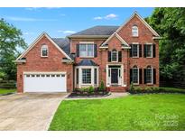 Traditional red brick home with black shutters, arched windows, attached garage, and lush green lawn at 6432 Morningsong Ln, Charlotte, NC 28269