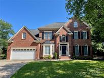Charming brick home featuring a well-manicured lawn, attached garage, and classic black shutters, enhancing its curb appeal at 6432 Morningsong Ln, Charlotte, NC 28269