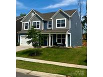 Charming two-story home featuring a well-manicured lawn and a combination of blue and gray siding at 7024 Wheyfield Dr, Charlotte, NC 28215