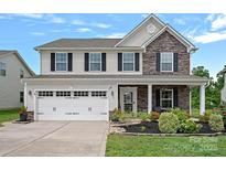Charming two-story home featuring stone accents, a manicured lawn, and an attached two-car garage at 7331 Millstone Sw Cir, Concord, NC 28025