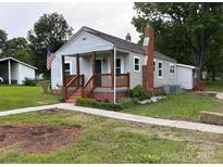 Charming single-story home with a covered front porch, an American flag, and a well-maintained yard at 410 Gann St, Lowell, NC 28098