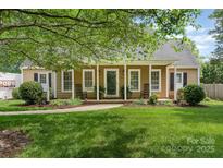 Charming home featuring a well-manicured lawn, inviting front porch, and attractive landscaping at 1012 Lightwood Dr, Matthews, NC 28105