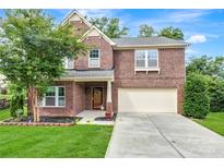 Charming two-story brick home featuring a well-manicured lawn, mature tree, and an attached two-car garage at 1017 Quail Run Ct, Indian Land, SC 29707