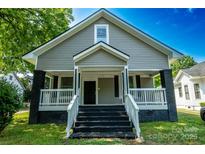 Charming home featuring a welcoming front porch, gray siding, and contrasting black accents on the brick foundation at 112 Hampton St, Chester, SC 29706