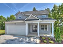 Charming gray two-story home featuring a covered porch, attached garage, and lush landscaping at 126 Meadow Glen Dr, Troutman, NC 28166