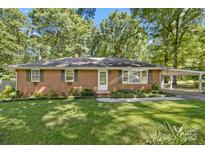 Charming single-story brick home featuring a well-manicured front yard and covered carport at 2522 Doster Rd, Monroe, NC 28112