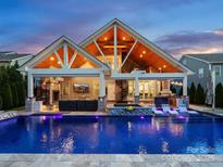 Stunning outdoor space with a pool, lounge chairs, outdoor kitchen, and spiral staircase under vaulted ceilings at 4049 Shadowbrook Rd, Waxhaw, NC 28173