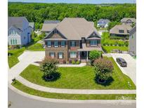 Beautiful brick home with a well-manicured lawn, mature trees, and a wide driveway leading to the garage at 424 Cassia Ct, Fort Mill, SC 29708