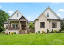Charming brick home with a covered porch, manicured lawn, and professionally landscaped flowerbeds at 867 Bellegray Rd, Clover, SC 29710