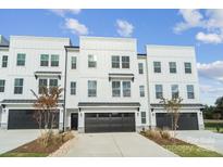 Modern townhome with white siding, black garage doors, and manicured landscaping on a sunny day at 9214 Delancey Ln # 62, Concord, NC 28027