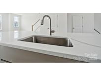 New construction home boasts a kitchen island with a stainless steel sink and modern faucet at 9214 Delancey Ln # 62, Concord, NC 28027