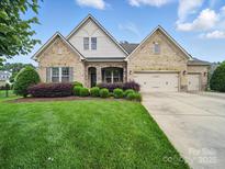 Charming brick home with a well-manicured lawn, beautiful landscaping, and a two-car garage at 1004 Fairbanks Ct, Indian Trail, NC 28079