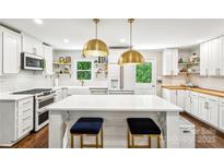 Bright kitchen featuring an island with seating, stylish lighting, white cabinets, and modern stainless steel appliances at 106 Phifer St, Fort Mill, SC 29715