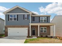 Two-story home with a brick and blue facade, attached garage, and a covered front porch at 11131 Cardinal Creek Ave, Charlotte, NC 28215