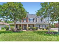 Charming two-story home with mature trees, manicured lawn, brick accents, and a welcoming front porch at 113 Dairy Farm Rd, Mooresville, NC 28115
