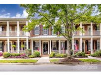 Charming brick townhome with inviting front porch and patriotic American flags on display at 139 Harper Lee St, Davidson, NC 28036