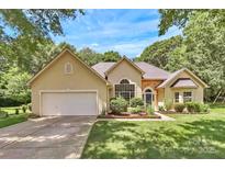 Charming single-story home with well-manicured lawn and attached two-car garage on a sunny day at 13930 Wild Heather Ct, Charlotte, NC 28273