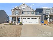 Charming two-story home featuring a stone facade, gray siding, and a two-car garage at 1708 Speartip Ln, Denver, NC 28037