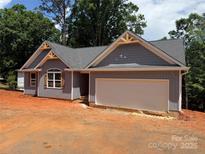 Charming single-story home with a gray roof, unfinished landscaping, and an attached garage at 2027 Marquesas Ave, Tega Cay, SC 29708