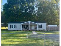 Charming home featuring a cozy front porch, well-maintained lawn, and a convenient storage shed in the backyard at 2291 Howell Rd, Midland, NC 28107