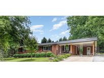 Charming single-story brick home featuring a covered porch and a well-manicured front yard with mature trees at 240 China Grove Rd, China Grove, NC 28123