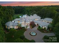 Stunning aerial view of a luxury home with lush landscaping, circular driveway, and a charming water fountain feature at 2926 Crane Rd, Waxhaw, NC 28173