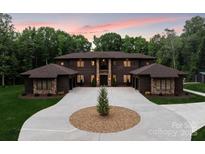 Stunning exterior elevation showcasing a large home with a circular driveway and lush landscaping at 3020 Brooks Mill Ln, Wingate, NC 28174