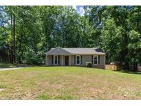 Charming single-story home with a well-maintained lawn and a backdrop of mature trees at 5233 Great Wagon Rd, Charlotte, NC 28215