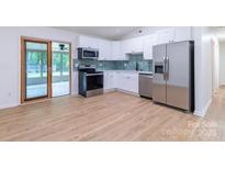 Bright kitchen features stainless steel appliances, white cabinetry, and adjacent sunroom at 5233 Great Wagon Rd, Charlotte, NC 28215