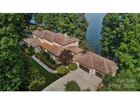 Lakefront home with expansive windows, tile roof, multiple garages, manicured grounds, and waterfront access at 9184 Greenwood Rd, Terrell, NC 28682
