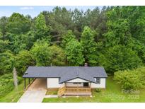 Charming one-story home featuring a wooden porch, carport, and surrounded by lush greenery at 103 Fleetwood Rd, York, SC 29745