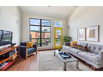 Bright living room boasts a large window, yellow door, and comfortable seating, creating a welcoming atmosphere at 115 E Park Ave # 409, Charlotte, NC 28203
