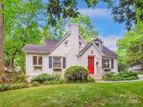 Charming painted brick home with a bright red front door, a chimney, and lush landscaping at 1219 Pinecrest Ave, Charlotte, NC 28205