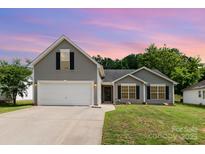 Charming gray home featuring a two-car garage and a well-manicured front lawn at 1533 Moss Creek Dr, Harrisburg, NC 28075