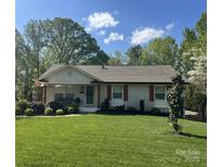 Charming home with a manicured lawn, red shutters, and beautiful landscaping at 1621 Brookdale Ave, Charlotte, NC 28210