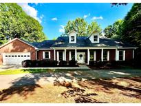 Charming brick home featuring a covered front porch, well-maintained landscaping and attached garage at 169 Wilcox Karriker Ln, Statesville, NC 28625