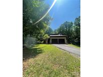 View of home on a wooded lot with an attached two-car garage and a paved driveway at 2505 White Thorne Ln, Waxhaw, NC 28173