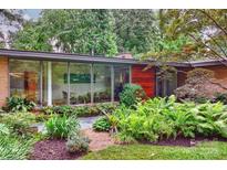 Mid-century modern home showcasing a brick facade, expansive windows, and lush, professionally landscaped greenery at 2600 Cloister Dr, Charlotte, NC 28211