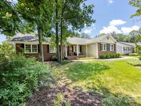 Charming brick home with well-manicured lawn, mature trees, and inviting front porch with black shutters at 4925 Cedar Forest Dr, Charlotte, NC 28226