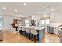 Bright kitchen features white cabinets, stainless steel appliances, island with seating, and an eat in dining area at 5917 Bridger Ct, Charlotte, NC 28211