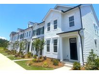 Charming row of white townhouses with black accents, well-manicured lawns, and inviting curb appeal at 8102 Jacey Ln # 24, Huntersville, NC 28078