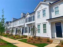 Charming street view of white townhomes with black shutters, well-maintained landscaping and sidewalks at 8102 Jacey Ln # 24, Huntersville, NC 28078