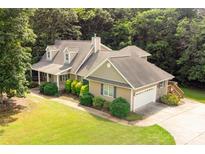 Aerial view of tan home with a shingled roof, surrounded by lush landscaping and mature trees at 8622 Lower Rocky River Rd, Concord, NC 28025