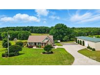 Picturesque aerial view of a home with a large, well-maintained lawn, a long driveway and mature trees at 9950 Foil Rd, Mount Pleasant, NC 28124
